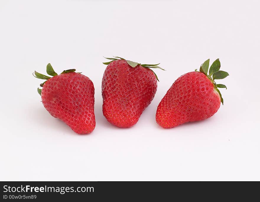 Three red, fresh and tasty strawberries on white background