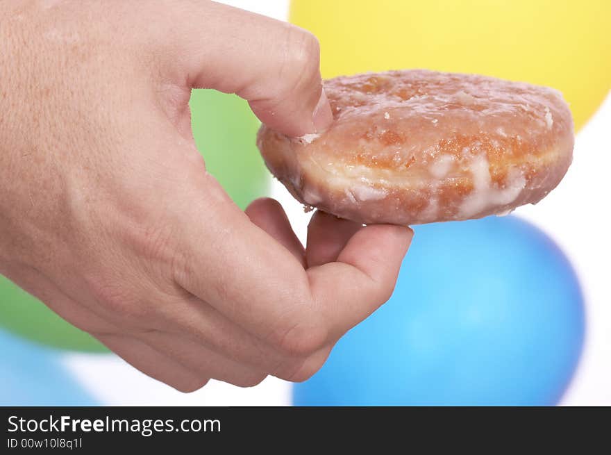 Hand holding donut over the colorful balloons