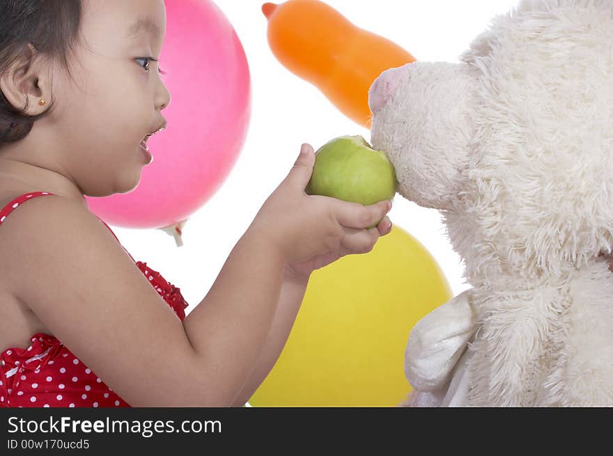 Toddler girl trying to feed teddy bear