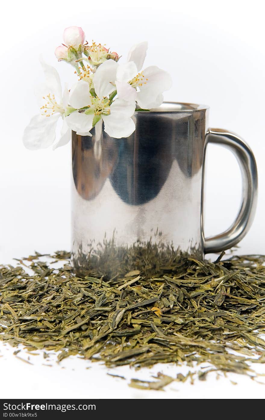 Cup of tea with flower and tea leafs, isolated on white background