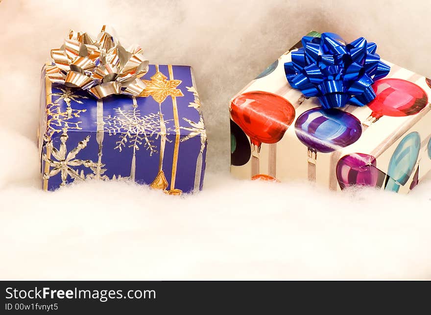 A closeup view of two colorfully wrapped Christmas presents on a fluffy white background. A closeup view of two colorfully wrapped Christmas presents on a fluffy white background.