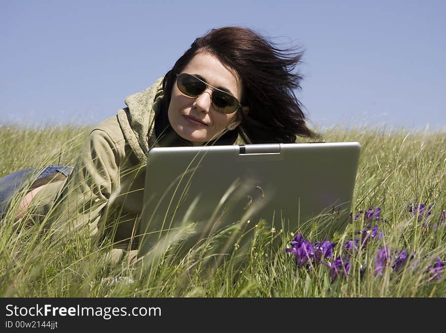 Woman laying down on grass with laptop. Woman laying down on grass with laptop