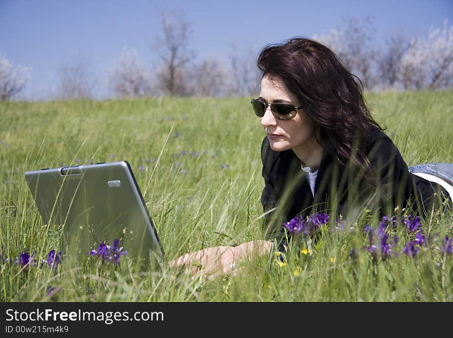 Woman laying down on grass with laptop. Woman laying down on grass with laptop