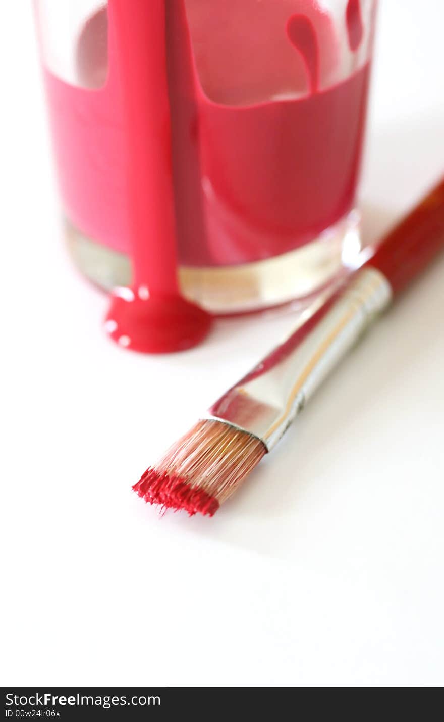 A cup of red paint with a paintbrush. A cup of red paint with a paintbrush