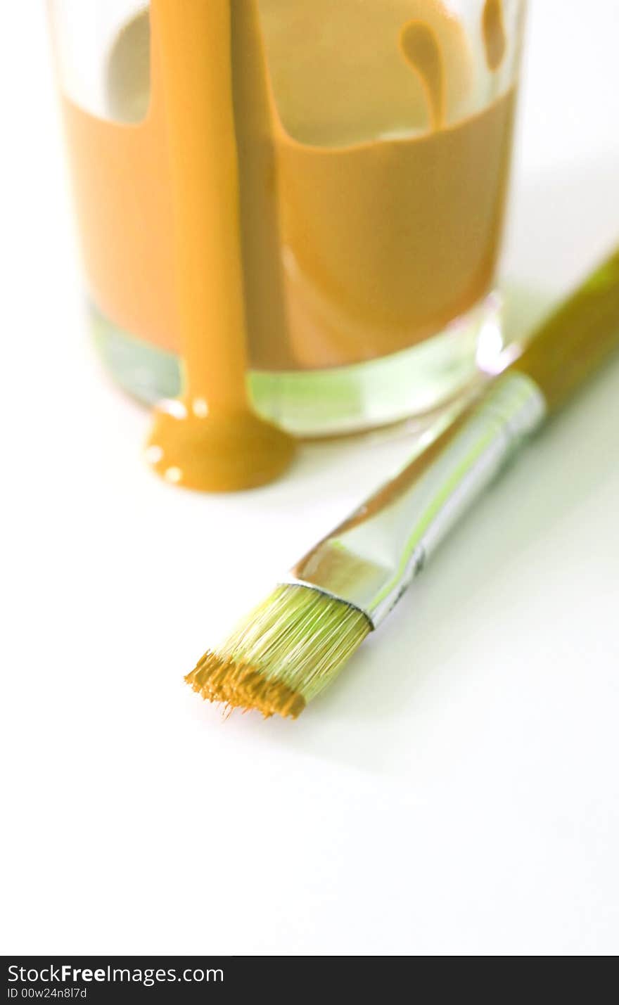 A cup of orange paint with a paintbrush. A cup of orange paint with a paintbrush