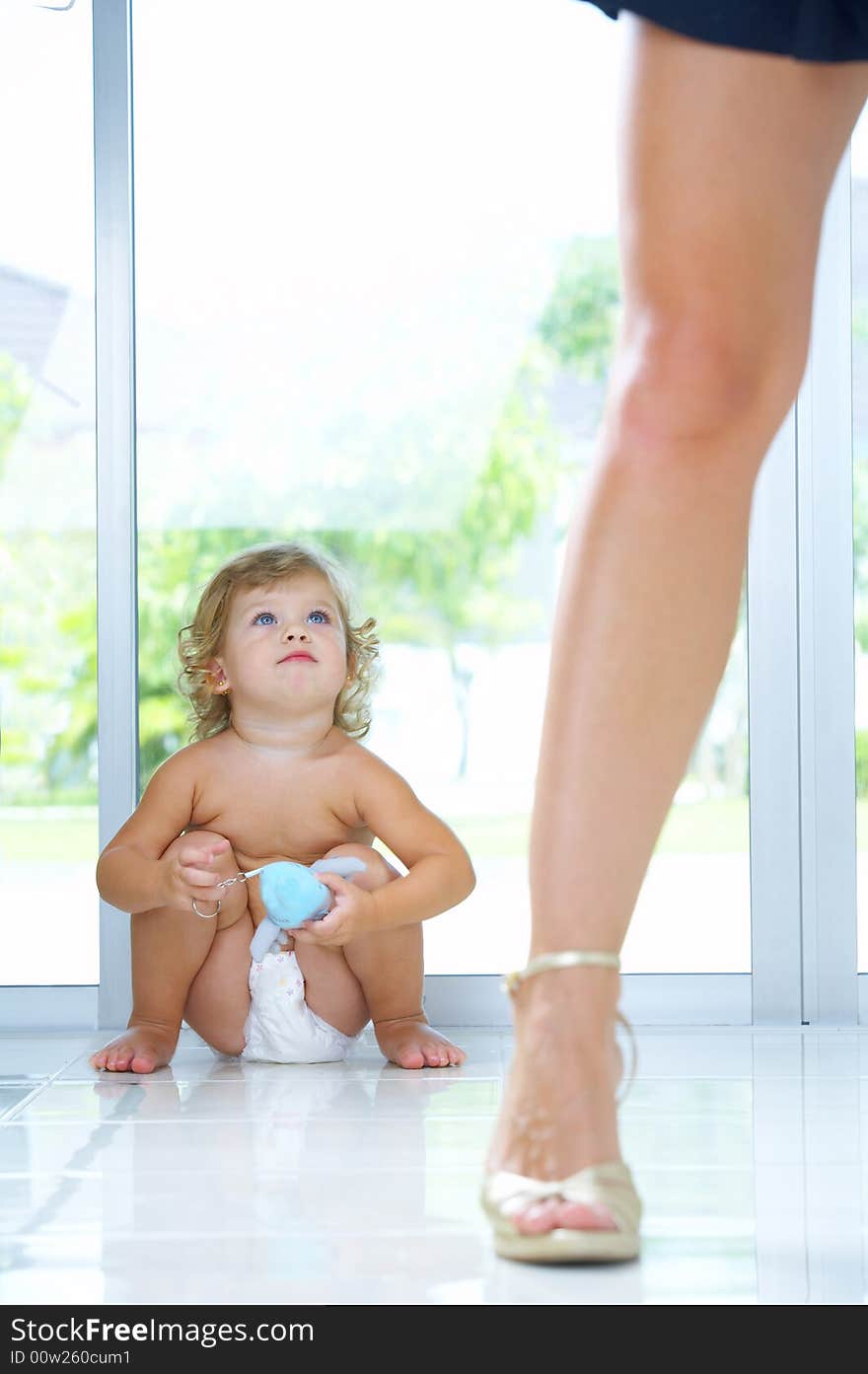 High key portrait of nice baby sitting by  mama’s leg. High key portrait of nice baby sitting by  mama’s leg