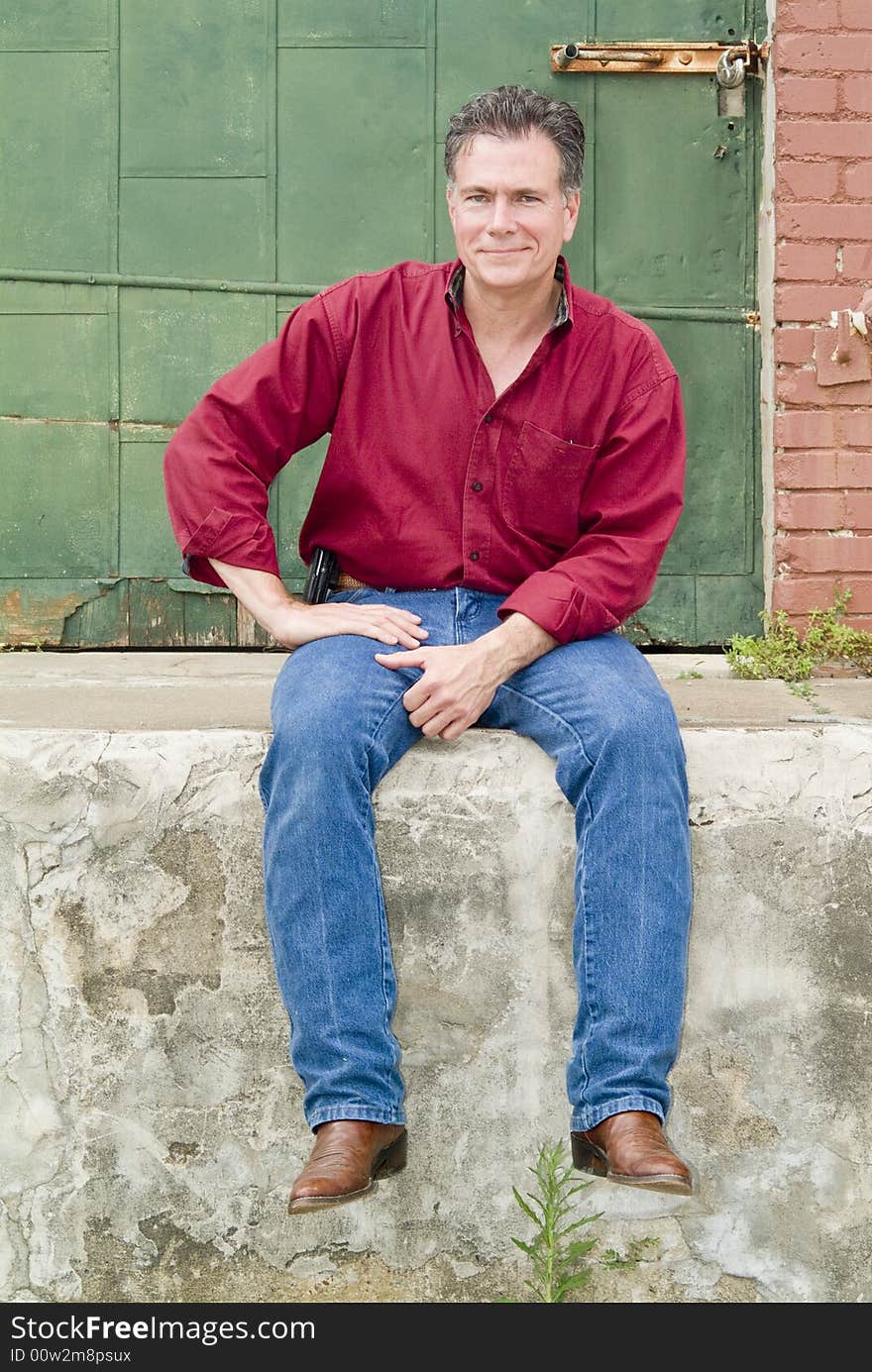 A man with a great smile, sitting on the walk in front of a large green door. A man with a great smile, sitting on the walk in front of a large green door.