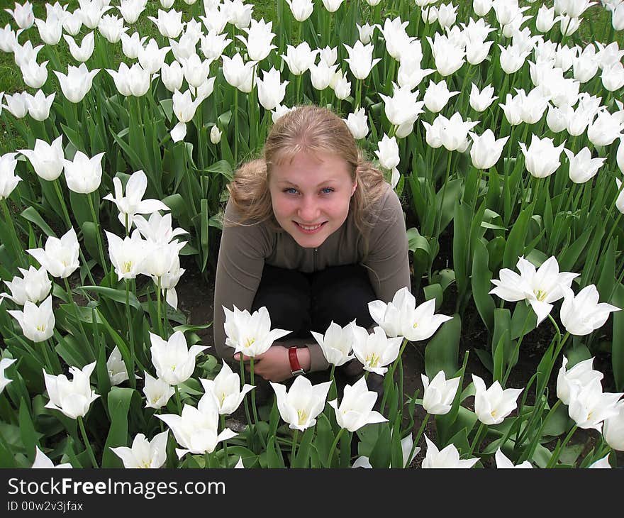 Beautiful girl sitting in the meadow among white tulips. Beautiful girl sitting in the meadow among white tulips