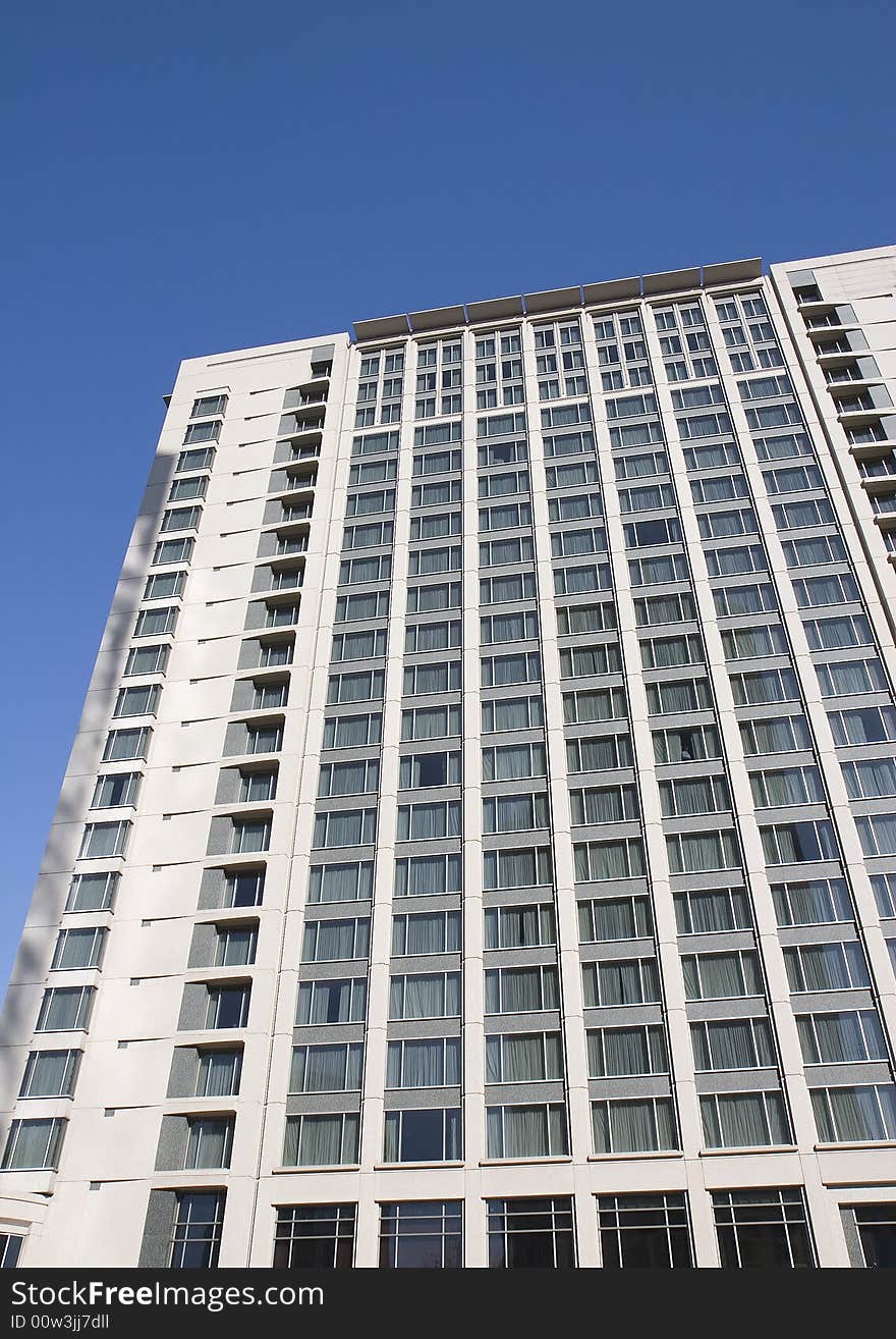 An massive modern high rise hotel in the city against a blue sky. An massive modern high rise hotel in the city against a blue sky