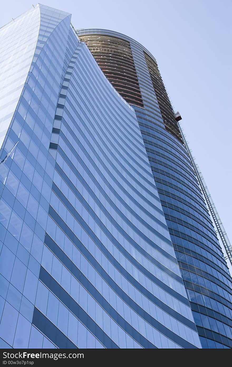 A modern curving blue glass office tower under construction. A modern curving blue glass office tower under construction