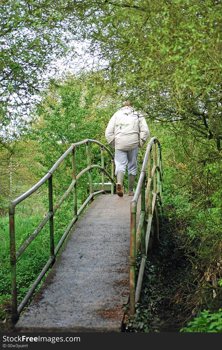 Shot of a man walking across a forest bridge. Shot of a man walking across a forest bridge