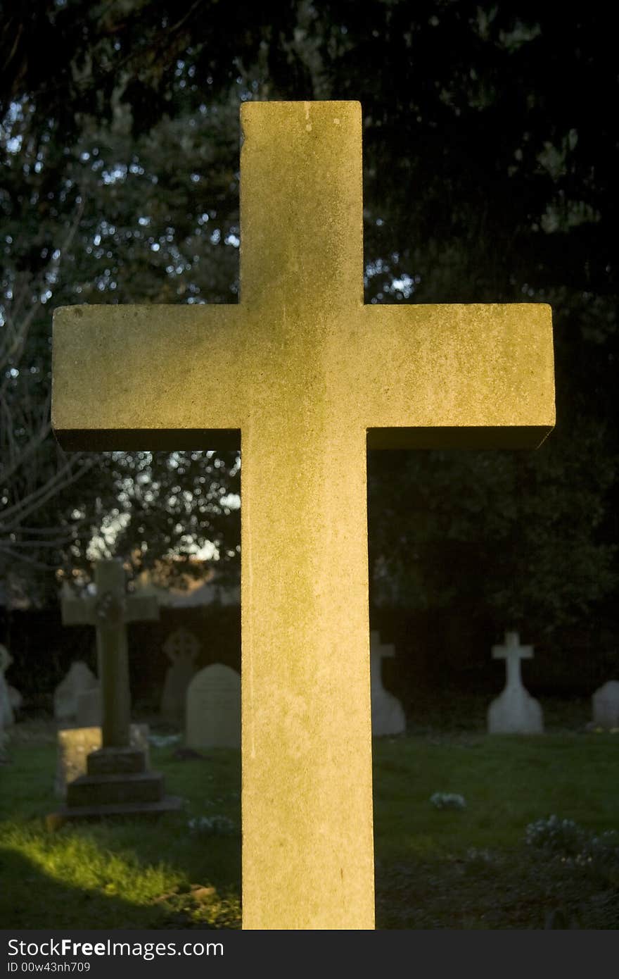 Cross in graveyard catches the light in English village. Cross in graveyard catches the light in English village