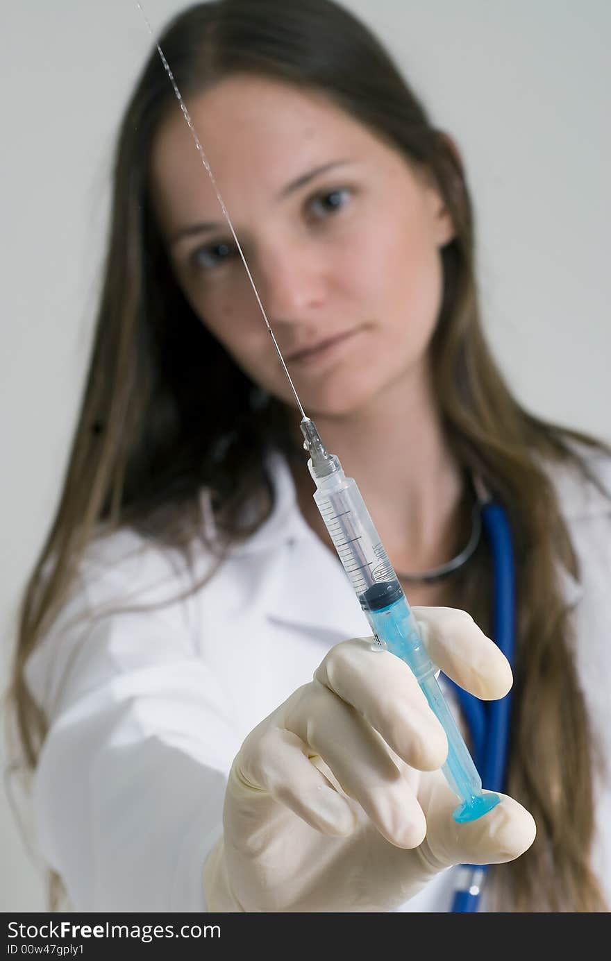 Young female doctor holding syringe in her outstretched arm. Isolated. Young female doctor holding syringe in her outstretched arm. Isolated.