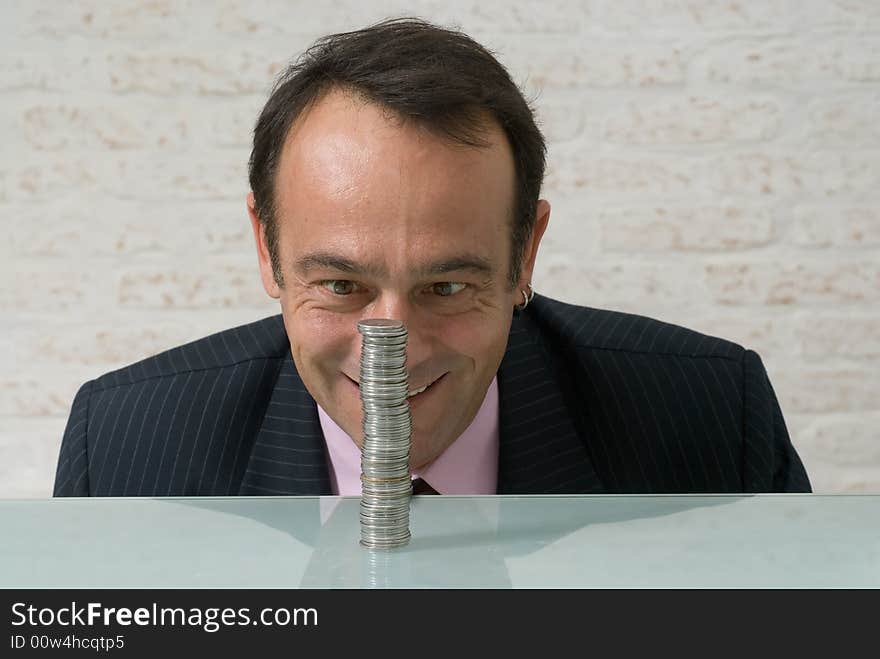 A shot of a businessman, with maniacal expression on his face, looking at a stack of quarters. A shot of a businessman, with maniacal expression on his face, looking at a stack of quarters.