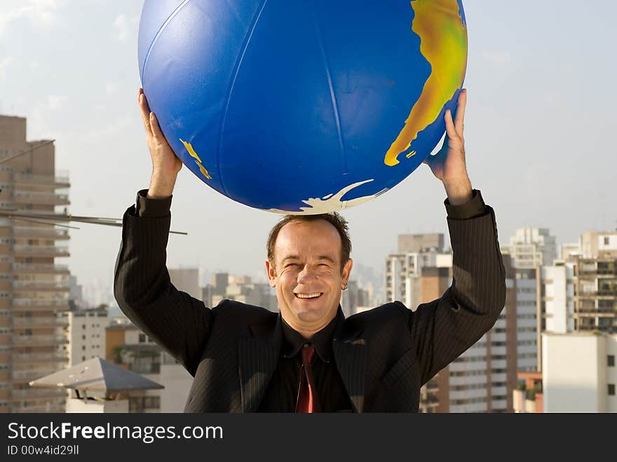 A businessman holding a large globe of the Earth in both hands above his head. A businessman holding a large globe of the Earth in both hands above his head.