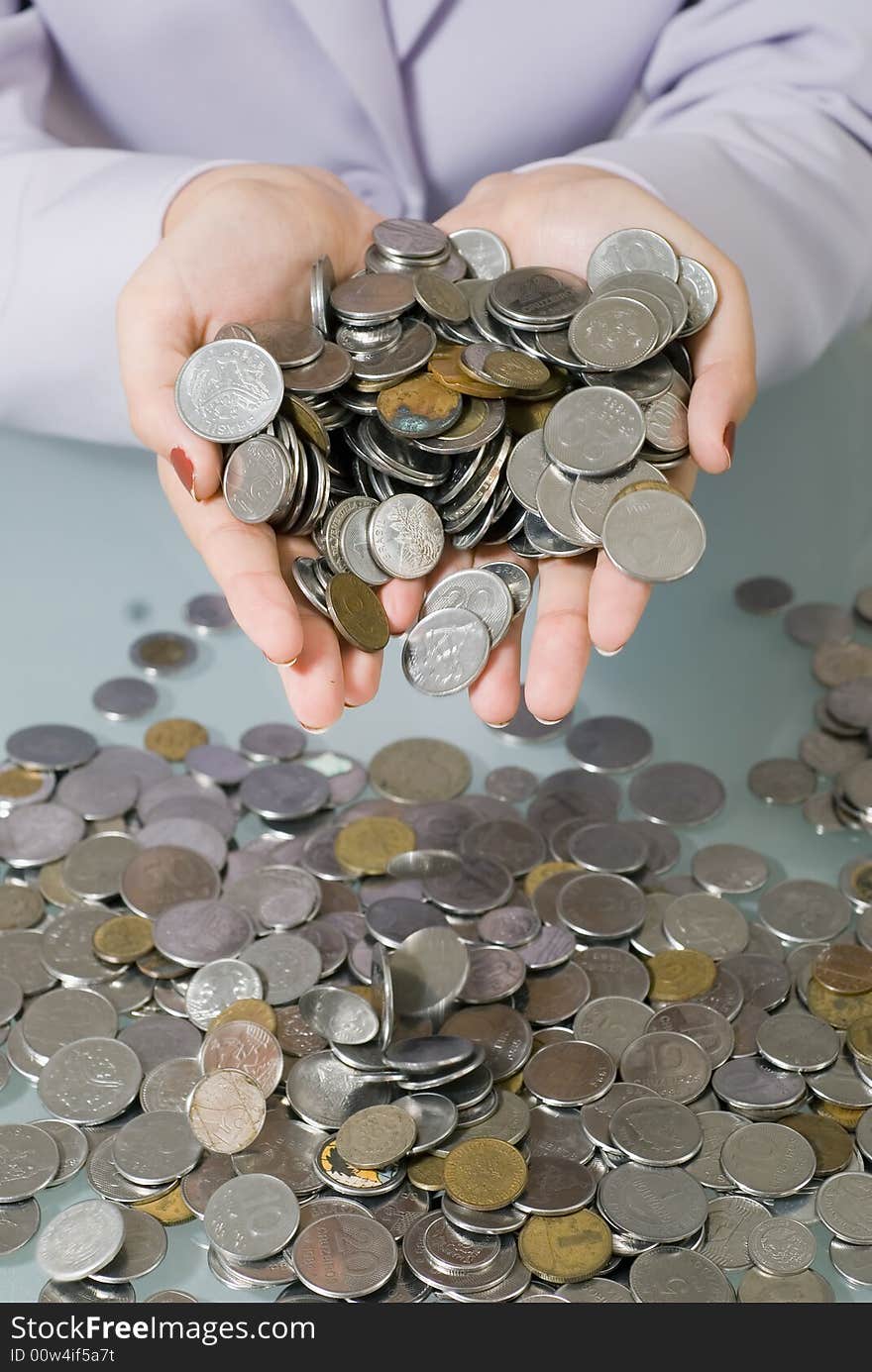 A close-up shot of a businesswoman holding coins above a pile of coins on glass desk. A close-up shot of a businesswoman holding coins above a pile of coins on glass desk.