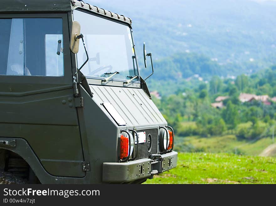 A large green parked truck on a mountainside. . A large green parked truck on a mountainside.