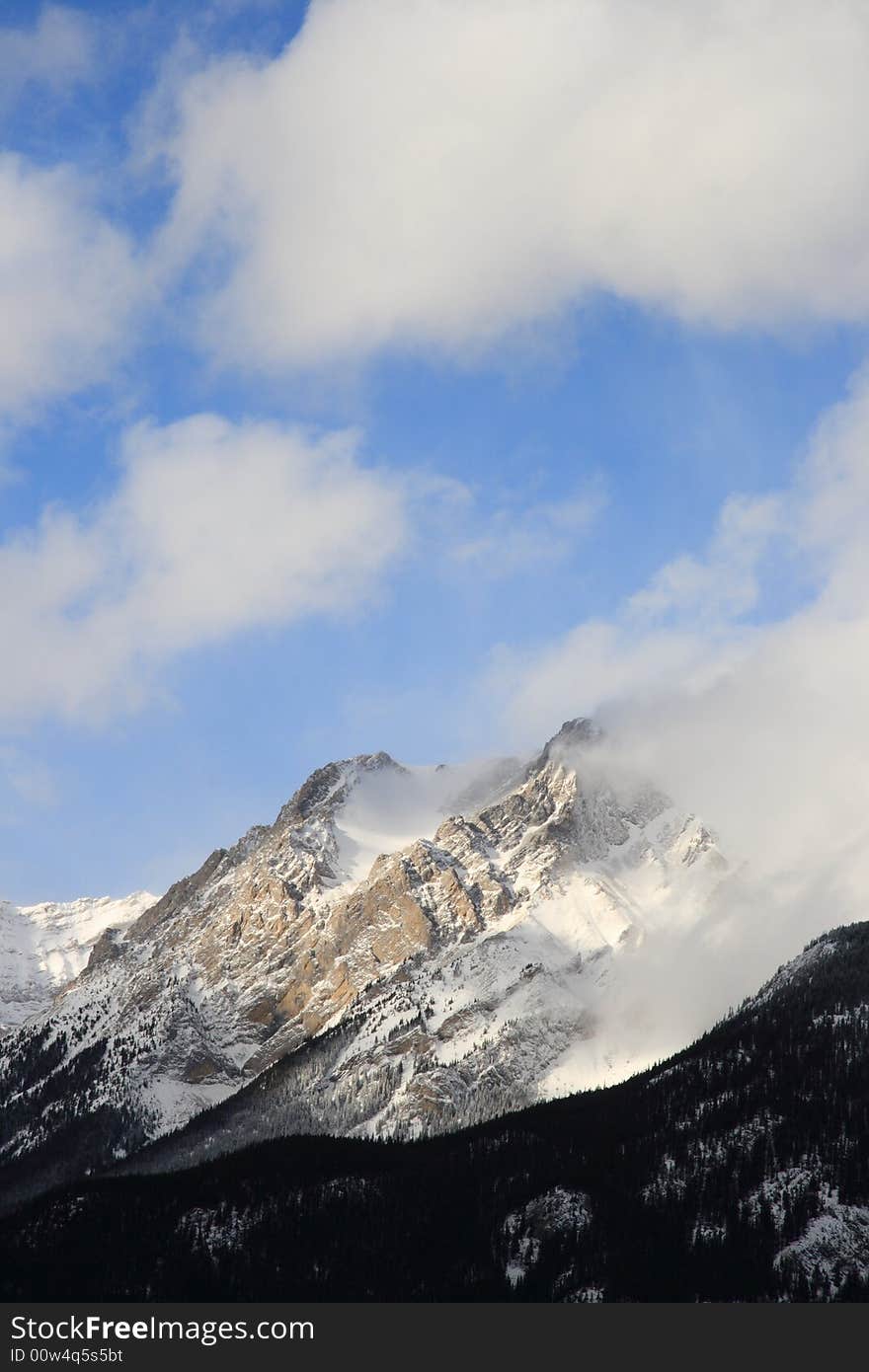 A lofty mountain peak hidden by clouds and shadows