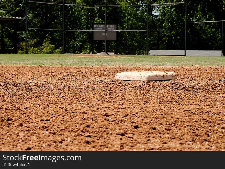 A baseball base on a little league field in focus. A baseball base on a little league field in focus.