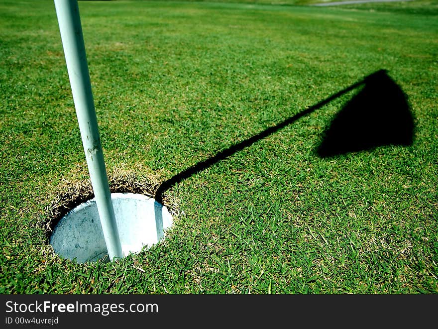 A golf hole on a green of a golfcourse with focus on the flag. A golf hole on a green of a golfcourse with focus on the flag.