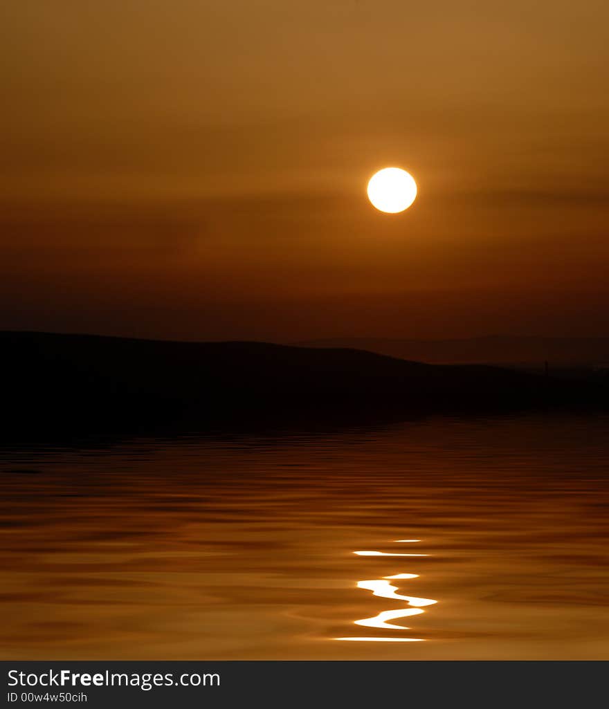 Sunset with sunstar and clouds in orange and golden light reflected in water. Sunset with sunstar and clouds in orange and golden light reflected in water