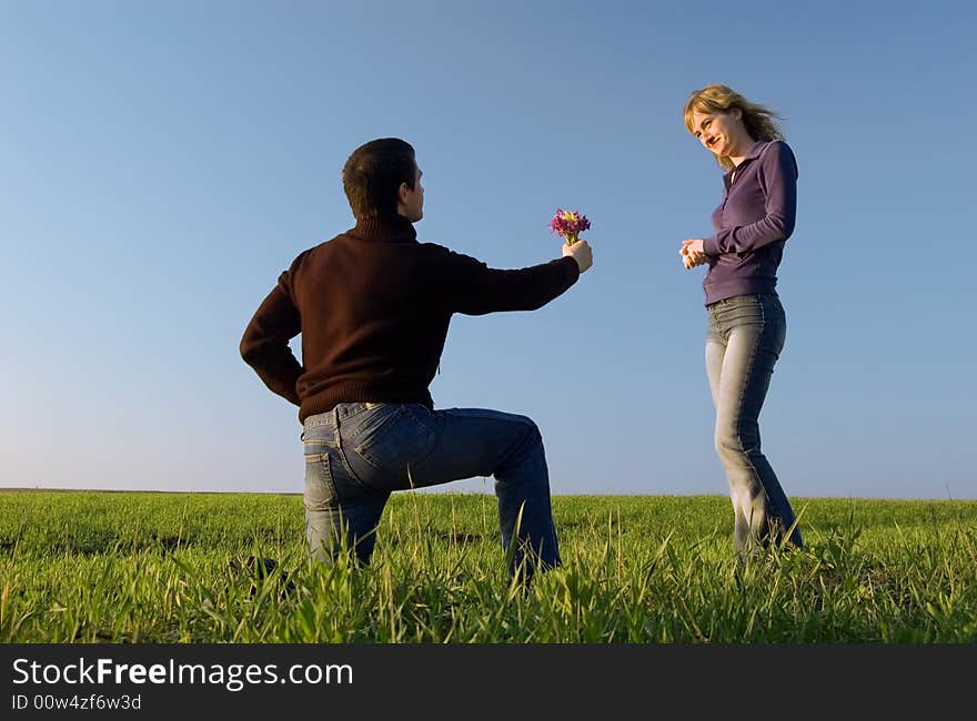 Guy stand on a knee and gives a bouquet to the girl. Guy stand on a knee and gives a bouquet to the girl