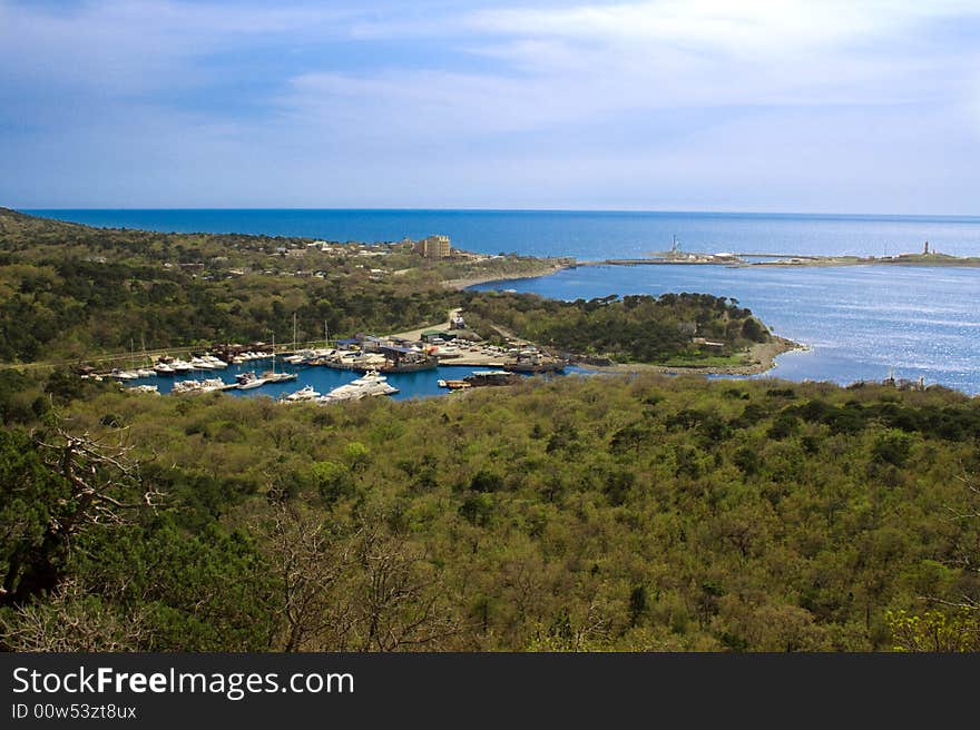 Small bay in mountains and a beacon on the sea