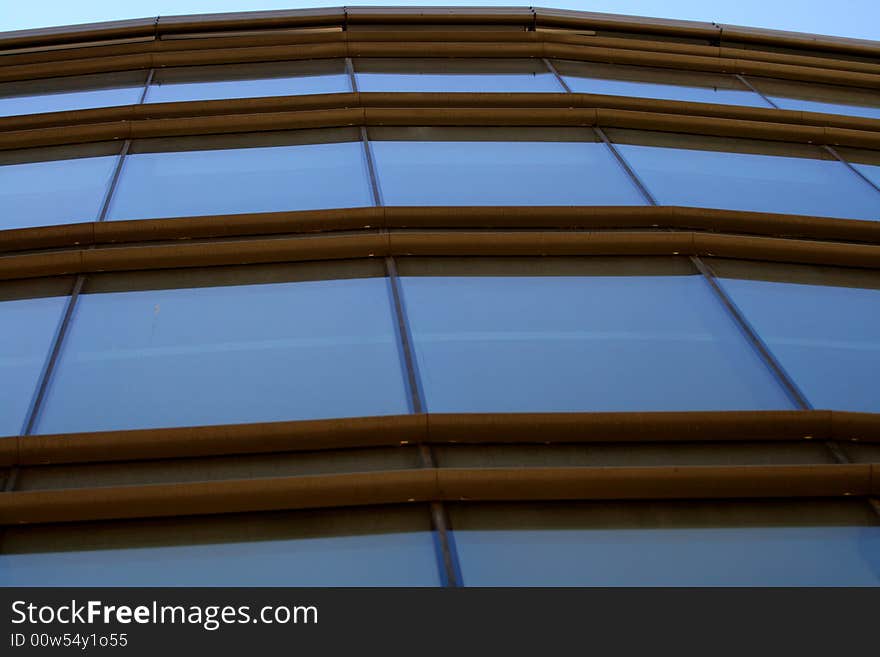 Glassy front reflective blue sky. Metal rusty brown cross supporting construction.