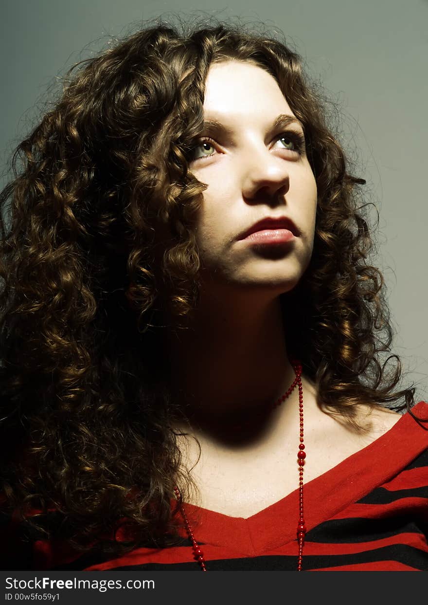 A portrait about a cute lady with white skin and long brown wavy hair who is looking up and admires something. A portrait about a cute lady with white skin and long brown wavy hair who is looking up and admires something