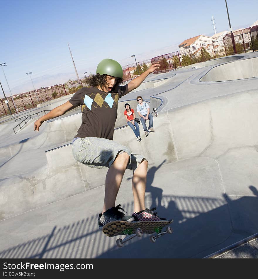 Teen skater does tricks at the skate park with his friends. Teen skater does tricks at the skate park with his friends