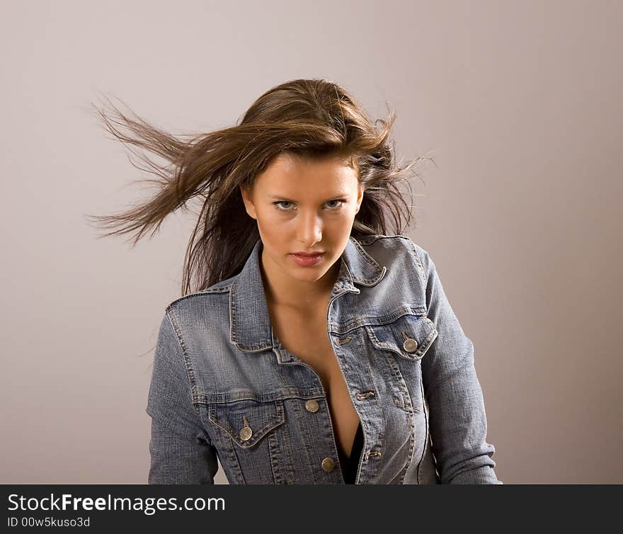 A beautiful young brunette with her denim jacket open exposing a black bra and her hair blowing in the wind. A beautiful young brunette with her denim jacket open exposing a black bra and her hair blowing in the wind