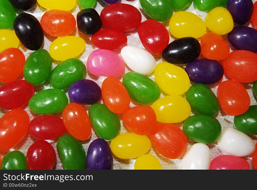 Colorful, tasty jelly beans spread out over a flat surface. The candy is viewed from directly above, and fills the frame entirely with orange, yellow, white, black, pink, green and red. Colorful, tasty jelly beans spread out over a flat surface. The candy is viewed from directly above, and fills the frame entirely with orange, yellow, white, black, pink, green and red.