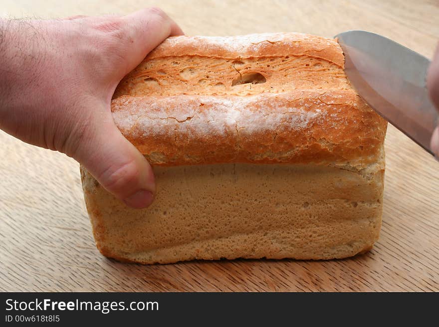 Cutting into a golden loaf of freshly cut bread. Cutting into a golden loaf of freshly cut bread