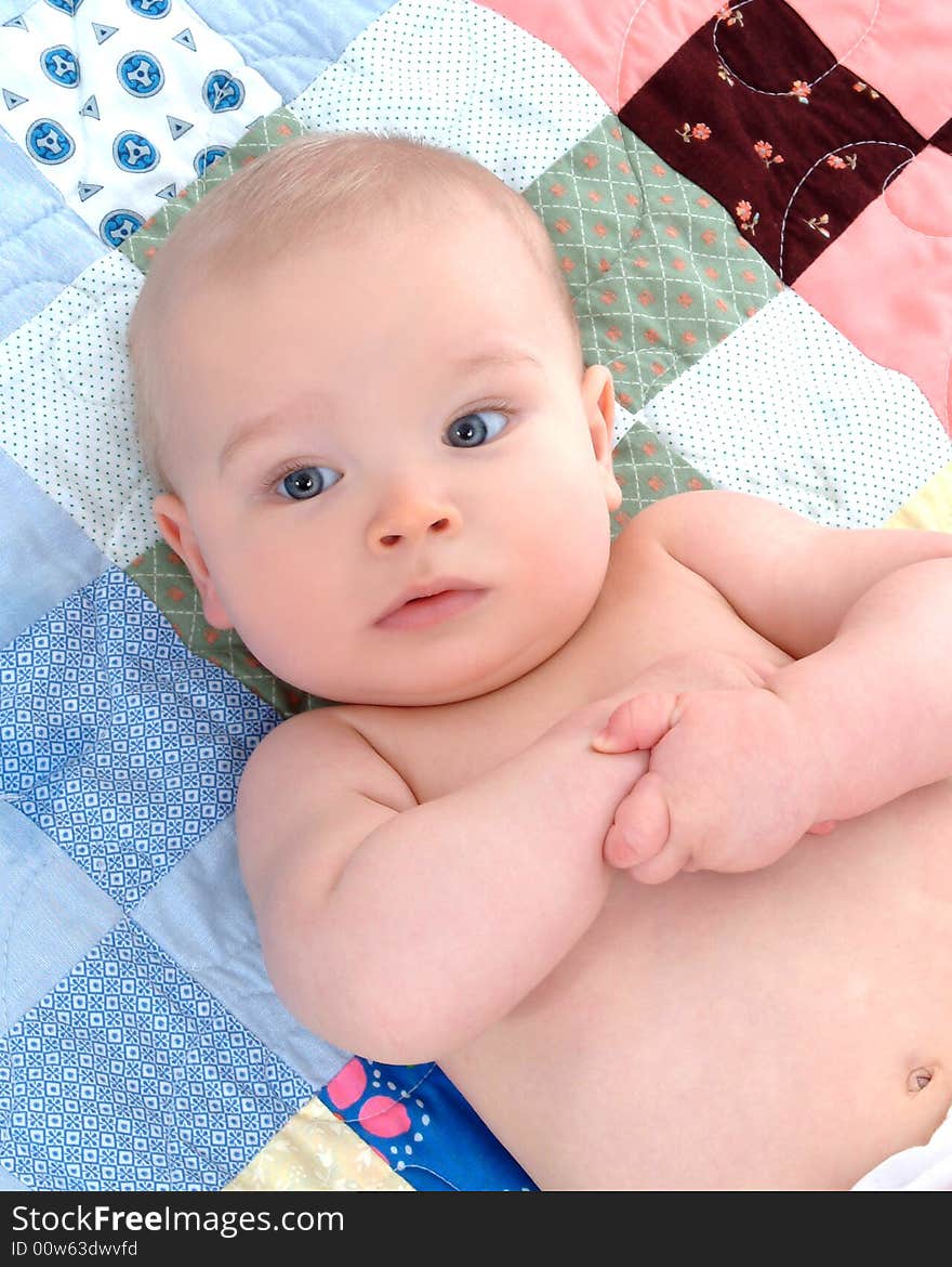 Cute baby lying on back on a multicolored quilt. Cute baby lying on back on a multicolored quilt