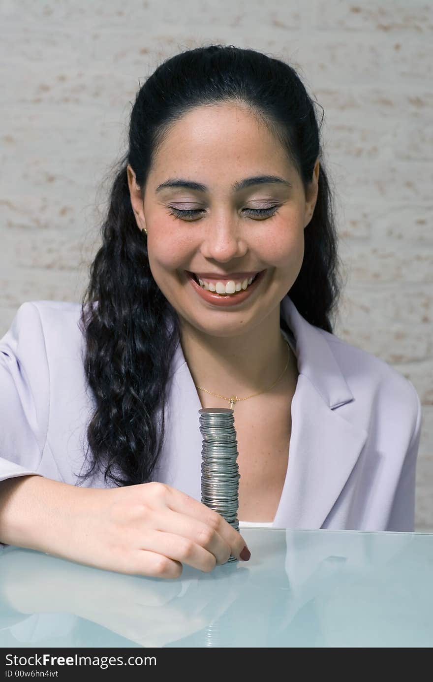 Latin american woman in a business suit with a big smile on her face looking at a big stack of coins. Latin american woman in a business suit with a big smile on her face looking at a big stack of coins