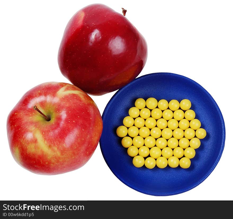 Blue plateful of yellow drops vitamin and red apples above them. isolated on white