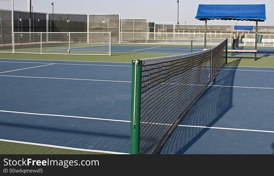 Tennis court net viewed from one end with bench. Tennis court net viewed from one end with bench