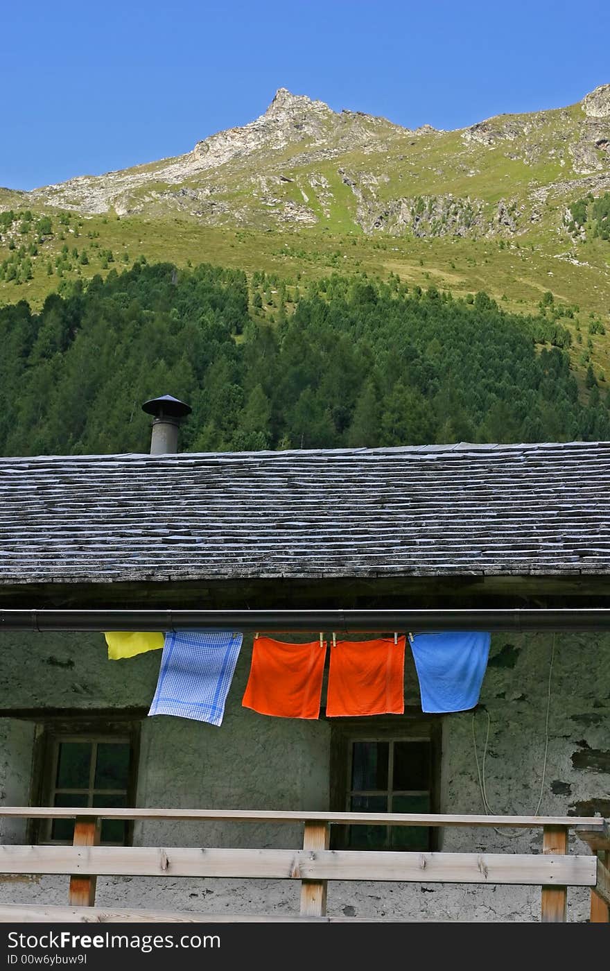 Alpine scenery with hut, mountain and colorful textiles