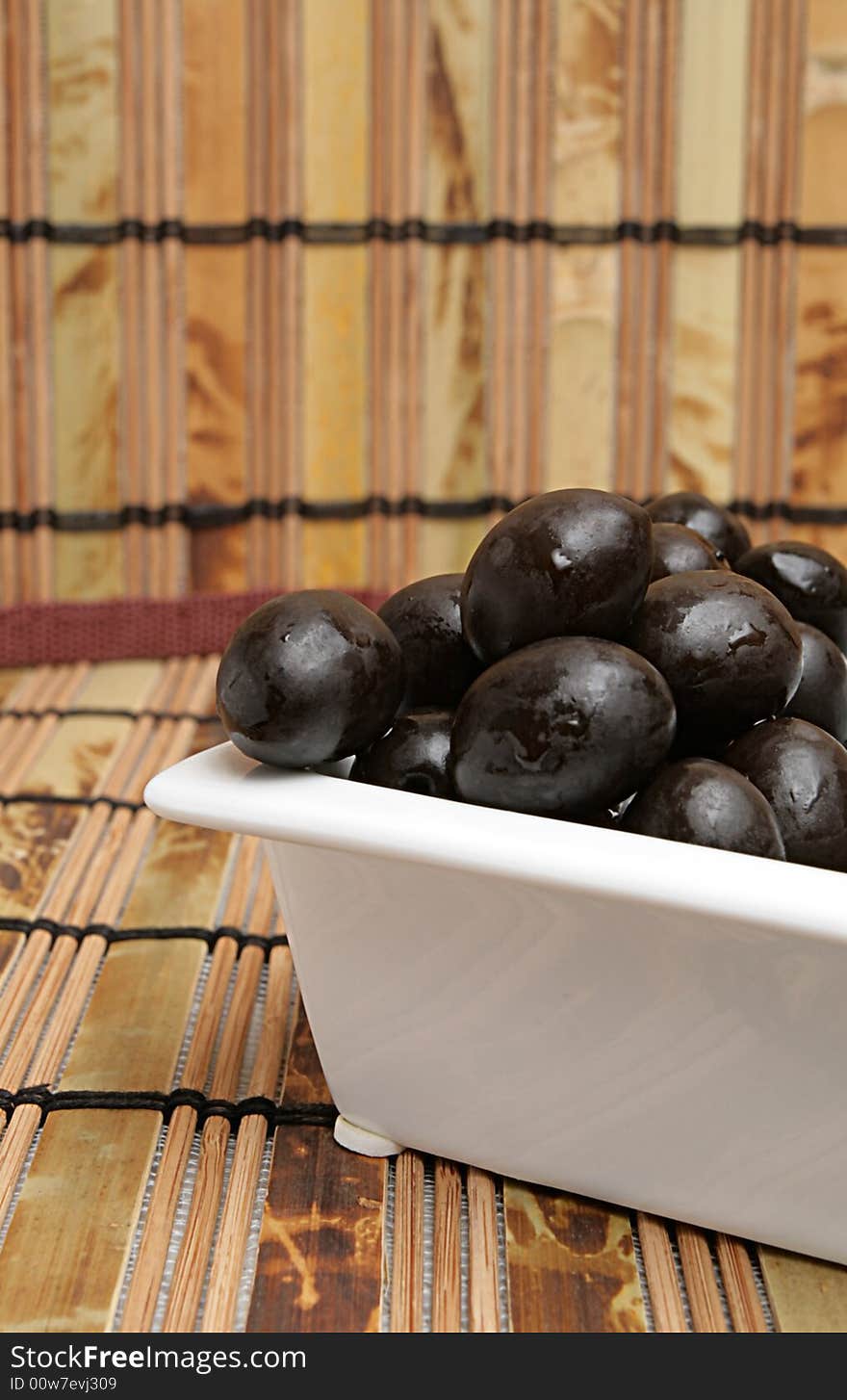 Olives in white plate on a mat