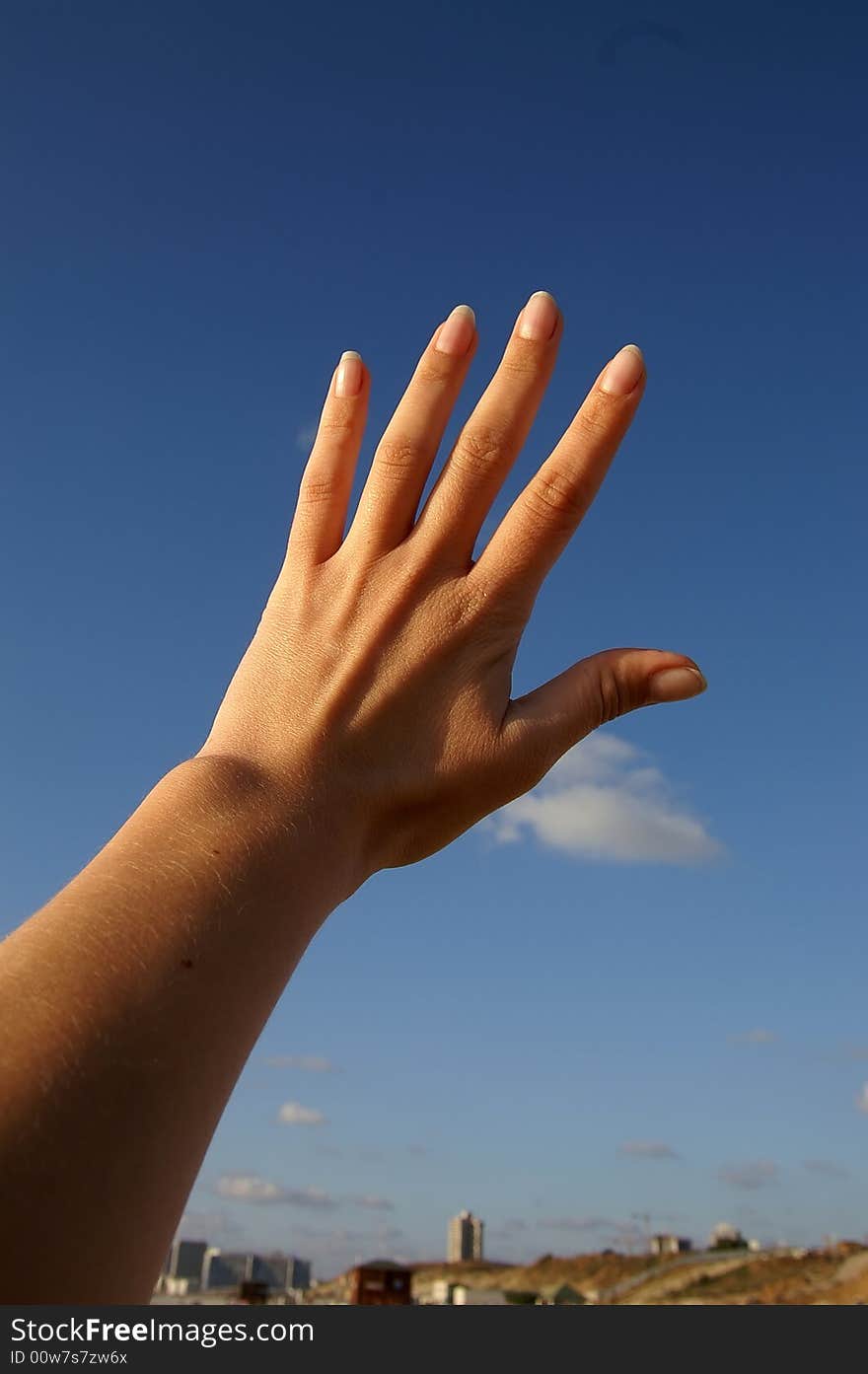 Female hand on blue sky background