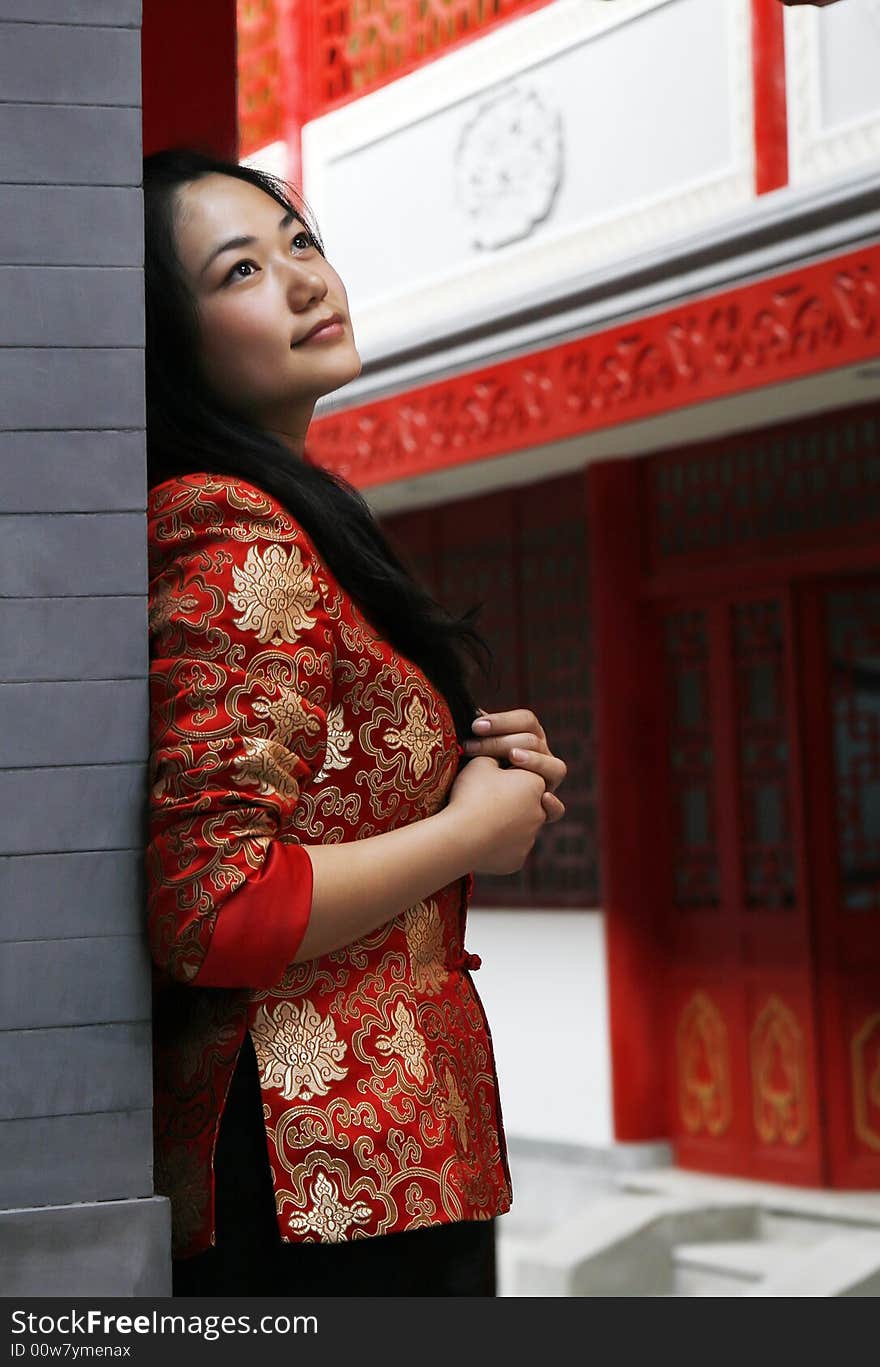 A Chinese girl in traditional dress stands at the front door of the ancient courtyard of China. Perhaps she is longing for the future. A Chinese girl in traditional dress stands at the front door of the ancient courtyard of China. Perhaps she is longing for the future.