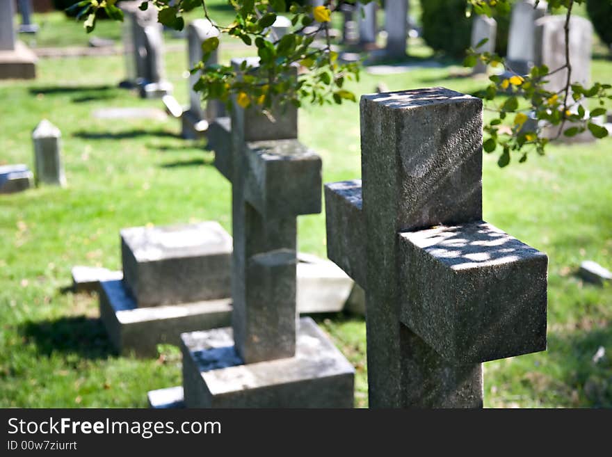 Granite stone crosses mark graves in an old country cemetery. Granite stone crosses mark graves in an old country cemetery.