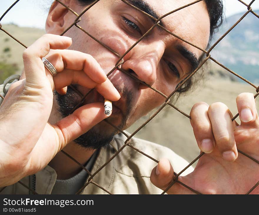 Portrait of man smoking through grid. Portrait of man smoking through grid