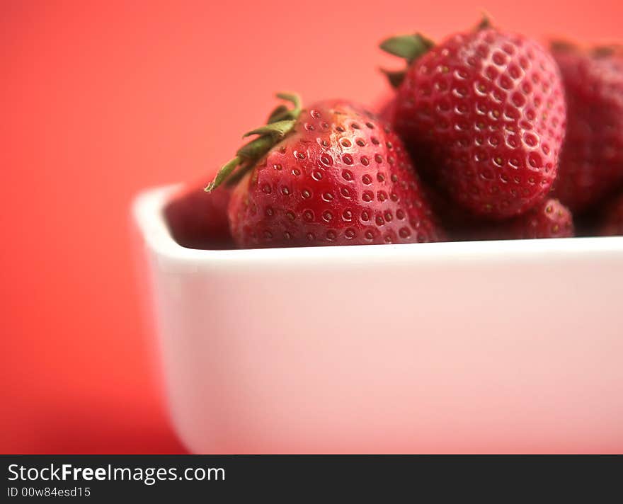 Ripe strawberries in white porceline with red background. Ripe strawberries in white porceline with red background