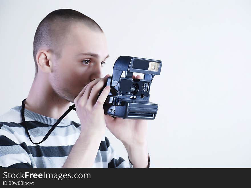 Young man photographer at white background with camera