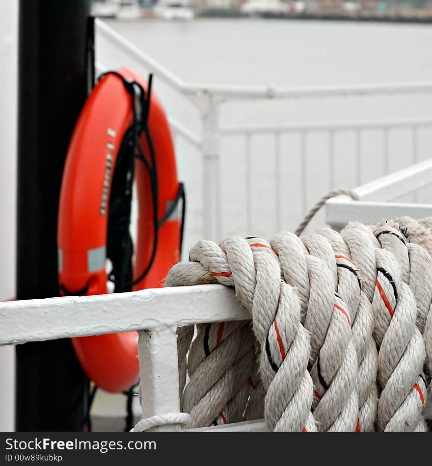 Strands of rope with life preserver in background on a river boat bow.