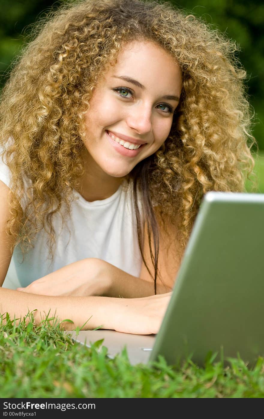 A beautiful young woman using a portable computer outside. A beautiful young woman using a portable computer outside