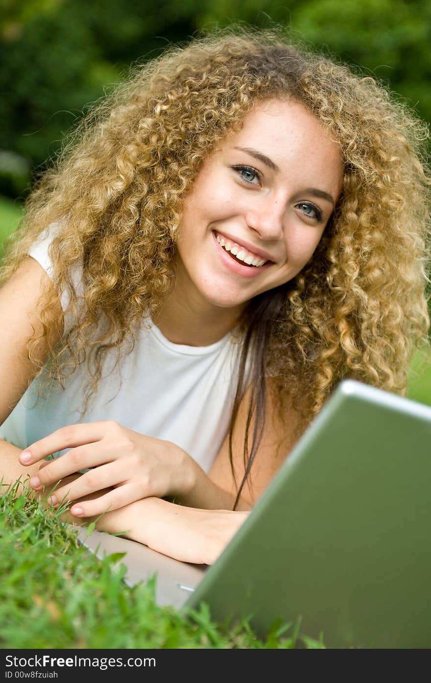 A beautiful young woman using a portable computer outside. A beautiful young woman using a portable computer outside