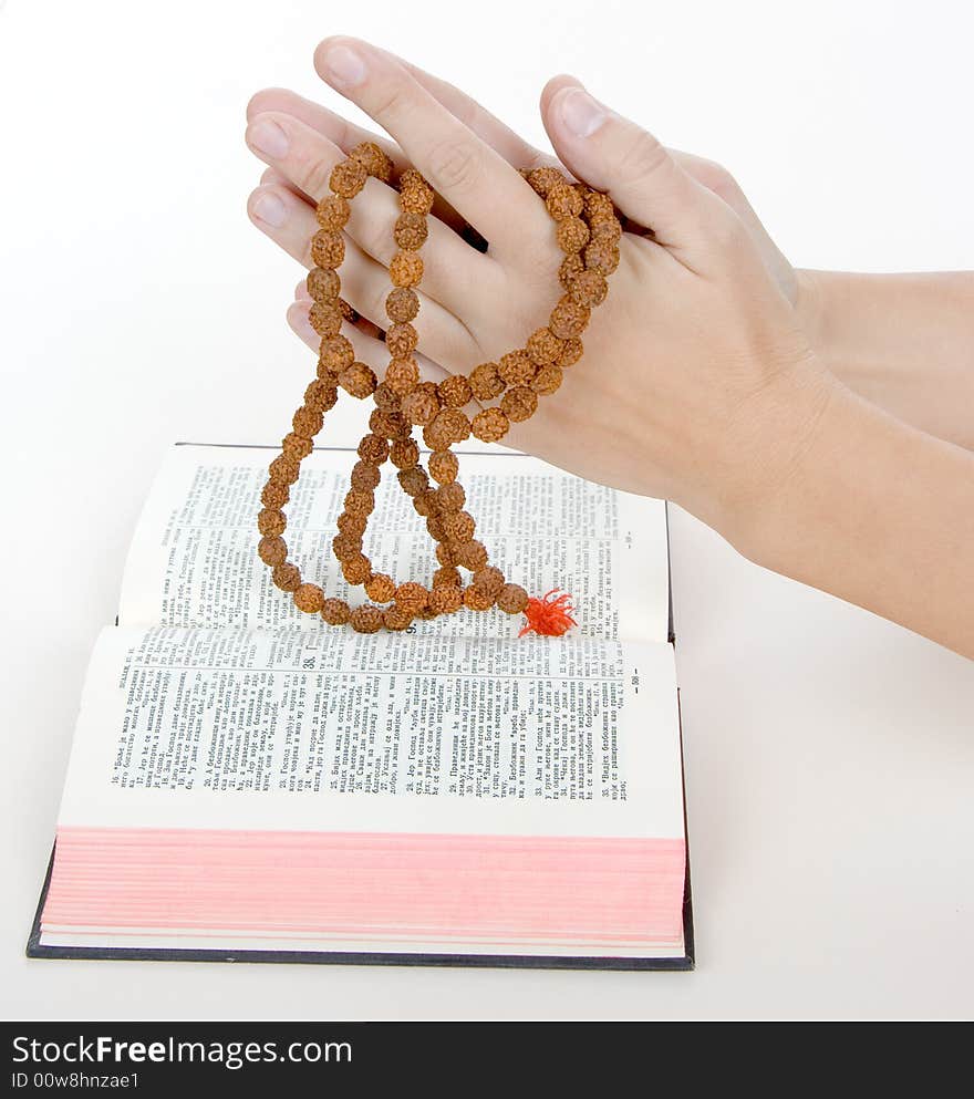 Praying with a rosary over a holy bible, background is white