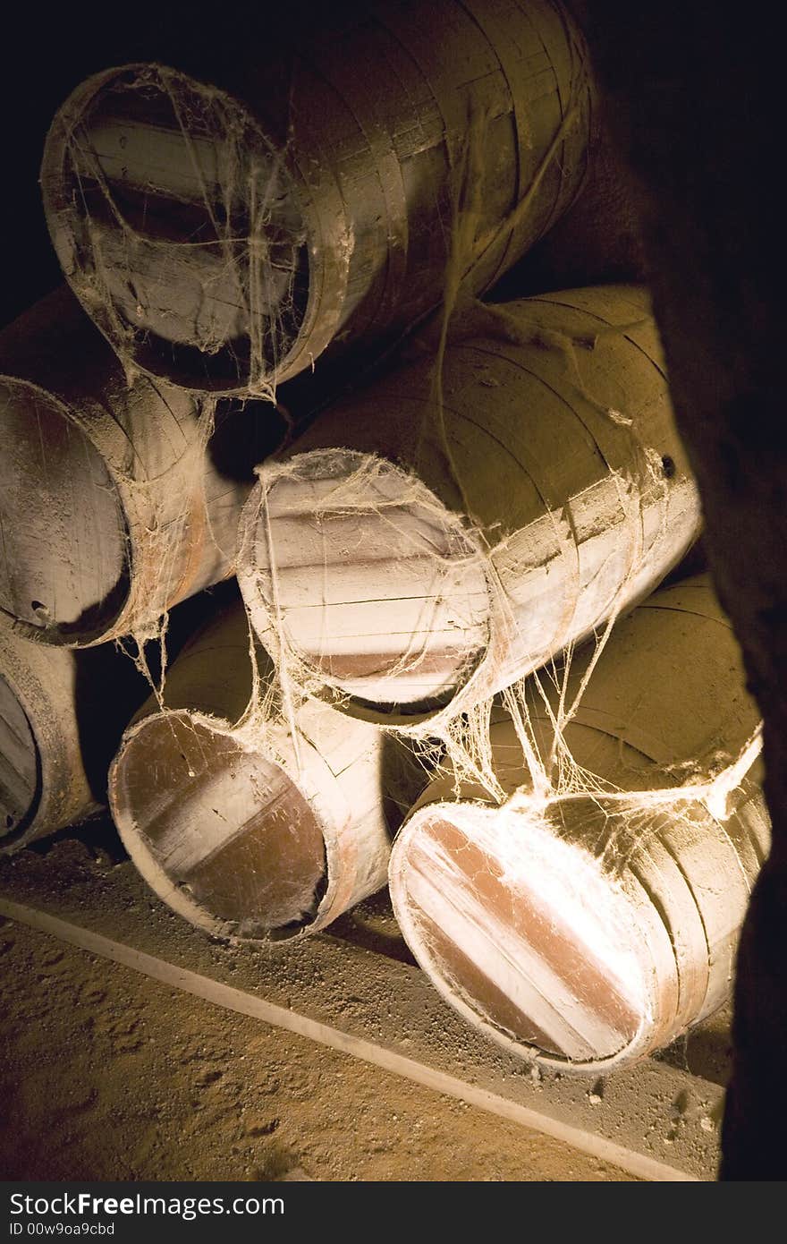 Old barrels with cobweb on the dark floor of a cellar